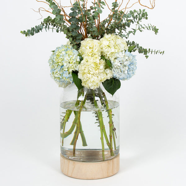 Let me be clear oversized glass vase with natural wood accents filled with flowers Galey Alix 